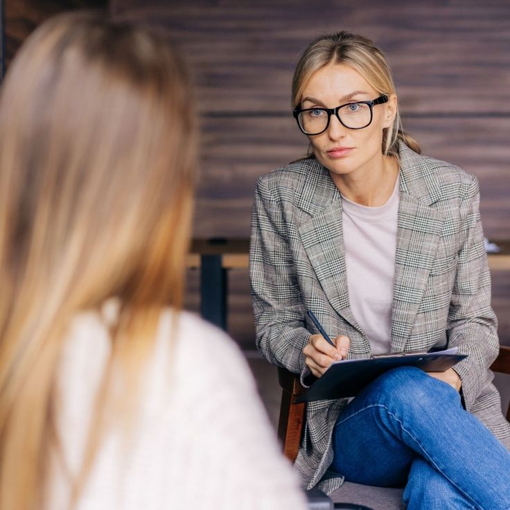Therapist taking notes while listening to a client during a counseling session
